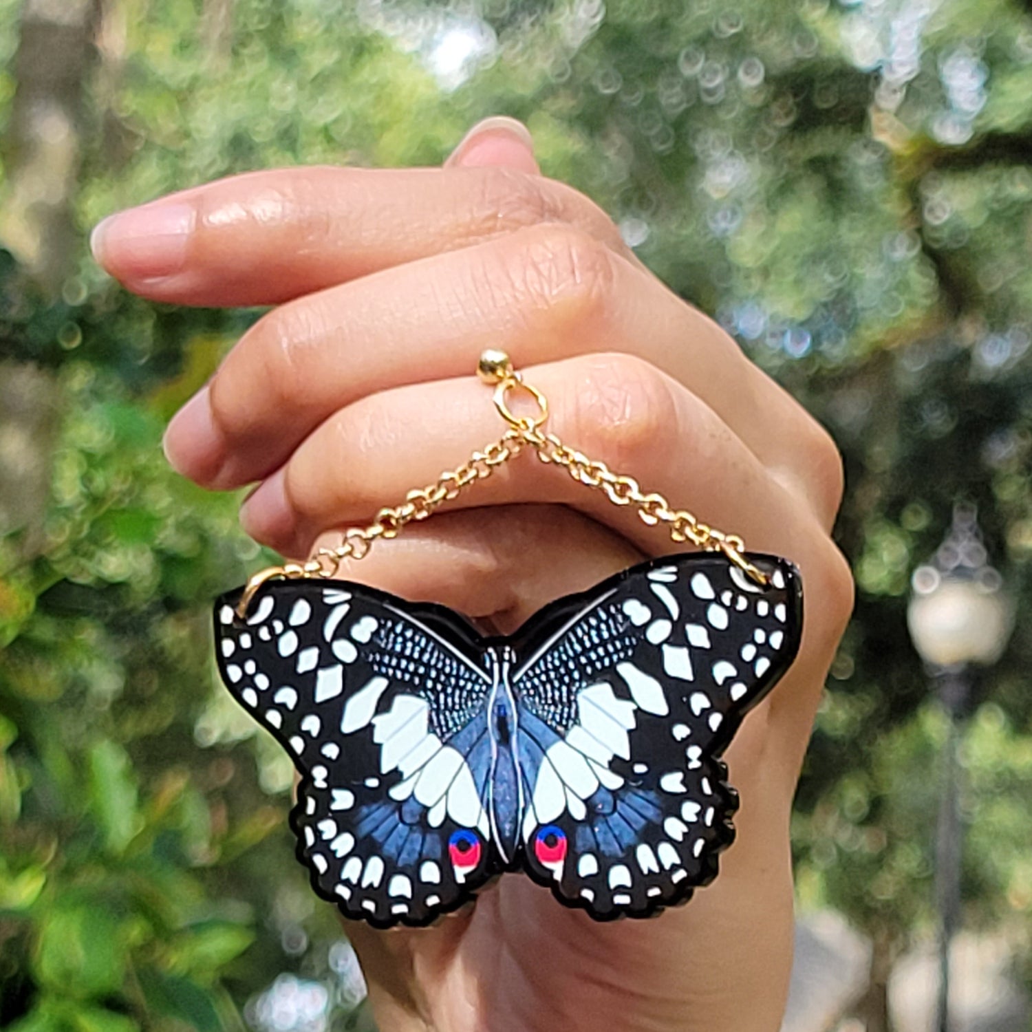 Medium sized black butterfly earrings held in a hand